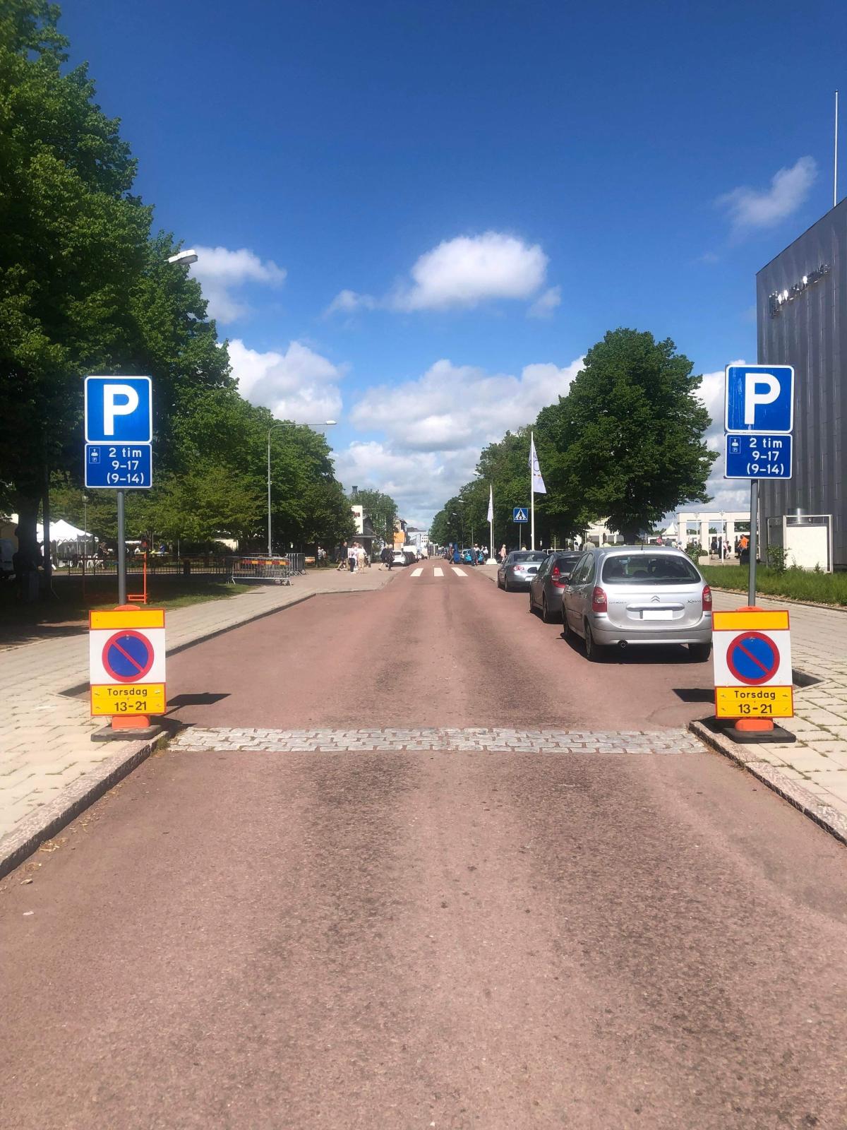 Bild på parkeringsförbudsskyltar och parkerade bilar längs med en gata i stadsmiljö