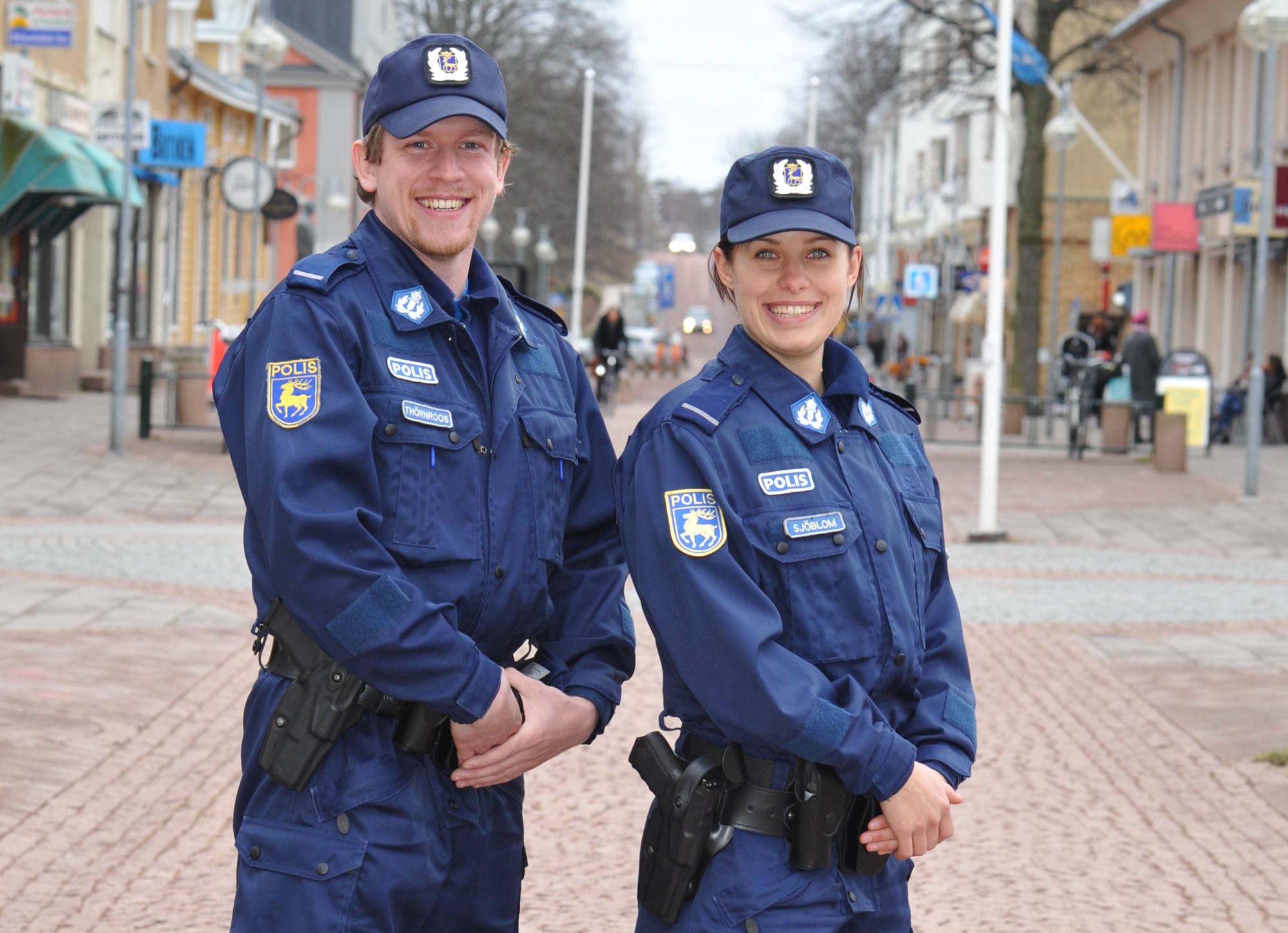 Två uniformerade poliser ler på gatan.